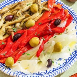 Escalivada topped with parsley and olives on a plate.