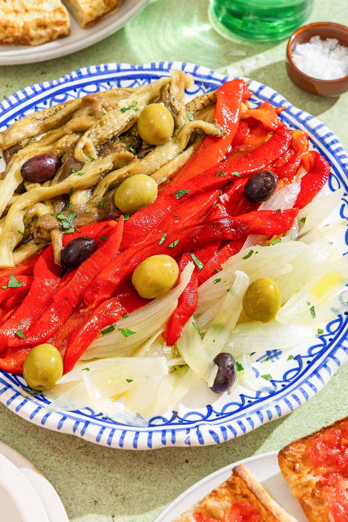 Escalivada topped with parsley and olives on a plate.