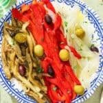 Escalivada topped with parsley and olives on a plate.