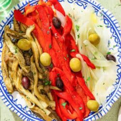 Escalivada topped with parsley and olives on a plate.