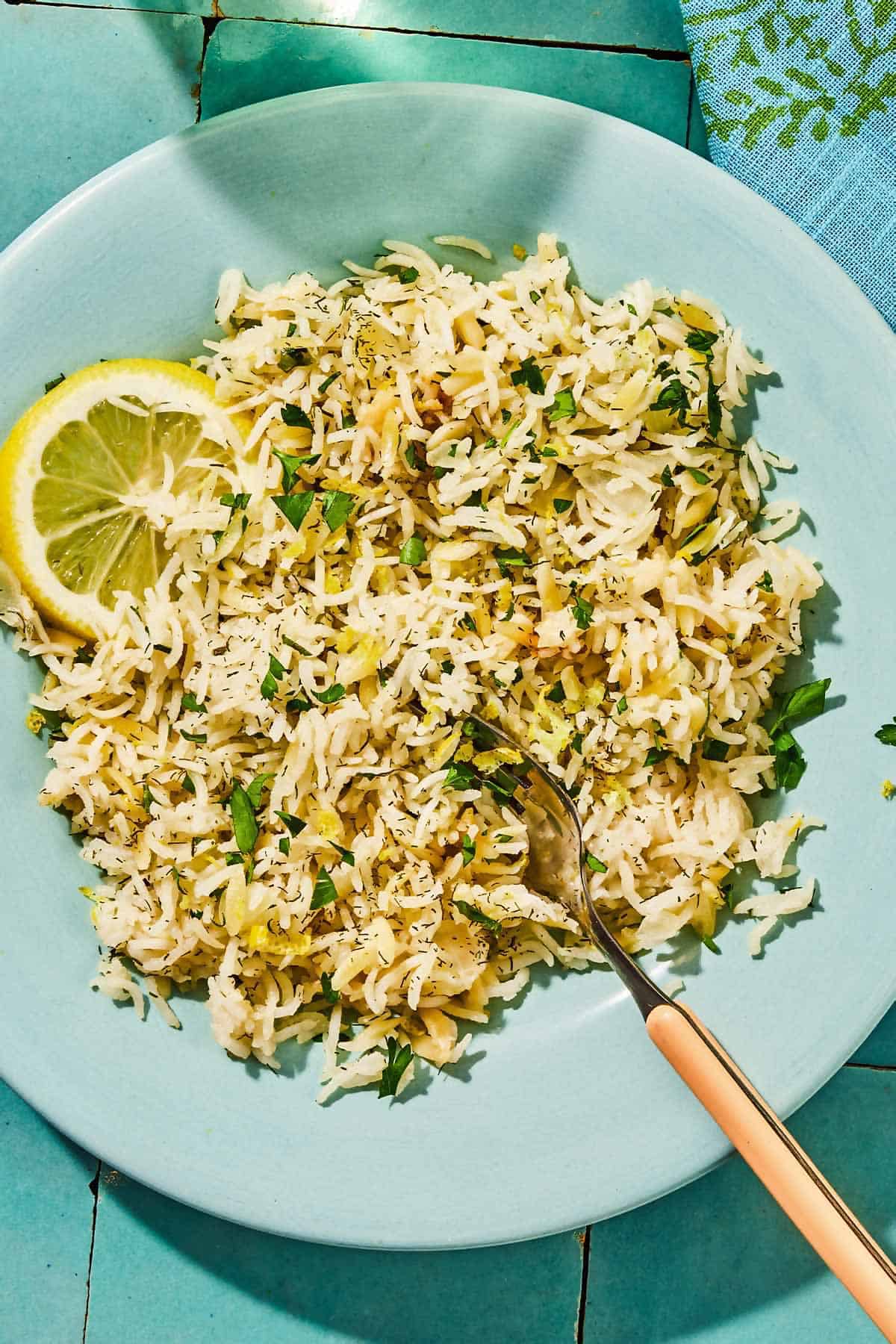 A serving of Greek lemon rice with a lemon wheel on a plate with a fork.