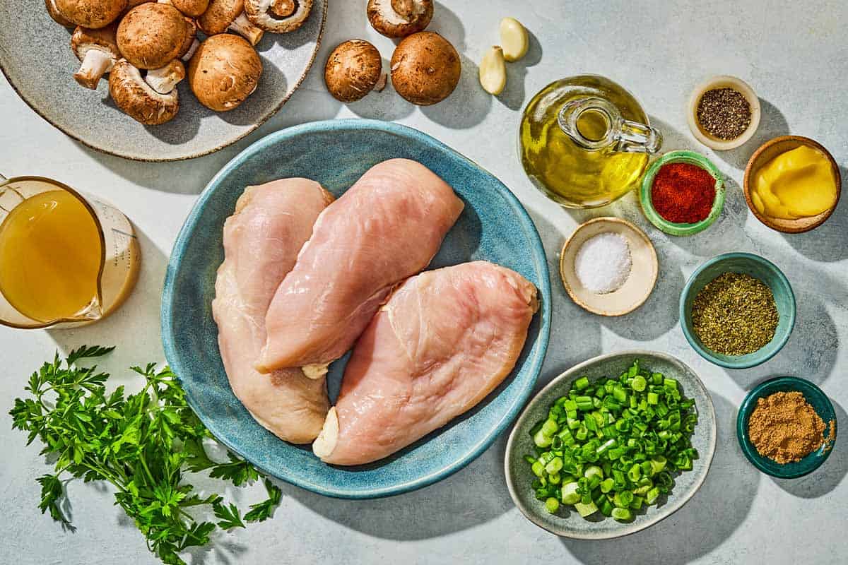 Ingredients for the chicken and mushroom recipe including chicken breast, salt, pepper, oregano, paprika, coriander, olive oil, ghee, mushrooms, chicken broth, green onions, garlic, and parsley.