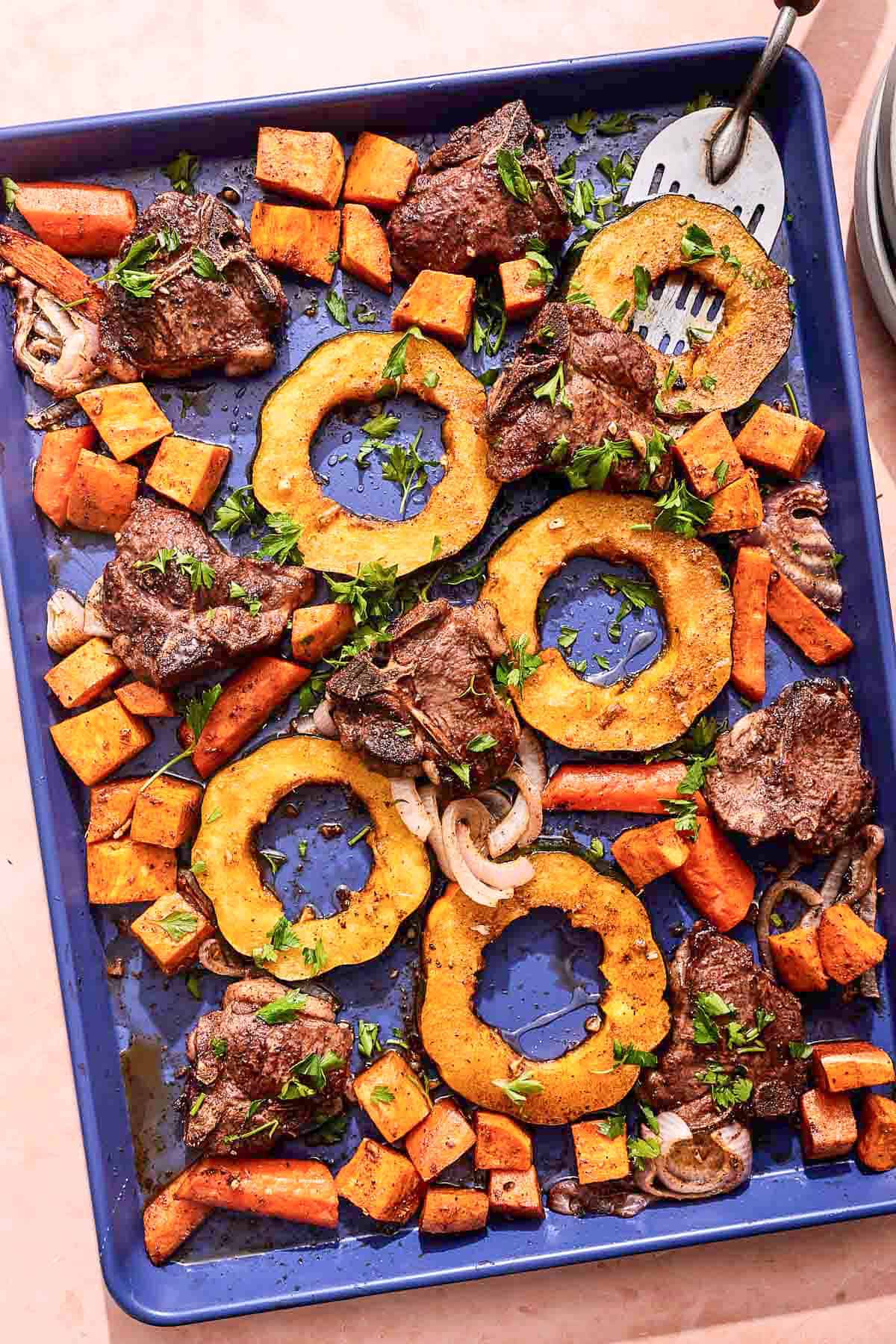 Baked lamb chops with vegetables on a sheet pan.