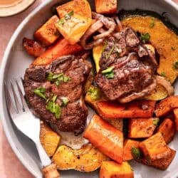 A serving of baked lamb chops with vegetables on a plate with a fork.