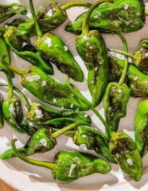 Padron peppers topped with flakey sea salt on a plate.