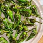 Padron peppers topped with flakey sea salt on a plate.