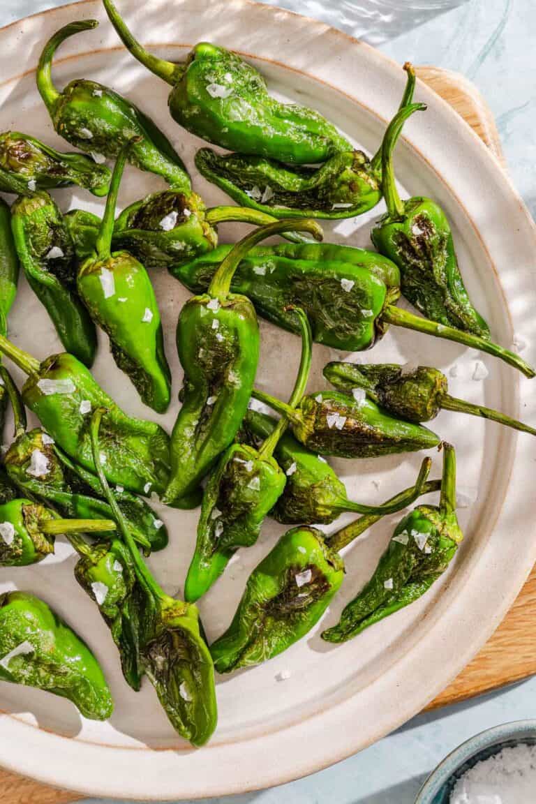 Padron peppers topped with flakey sea salt on a plate.