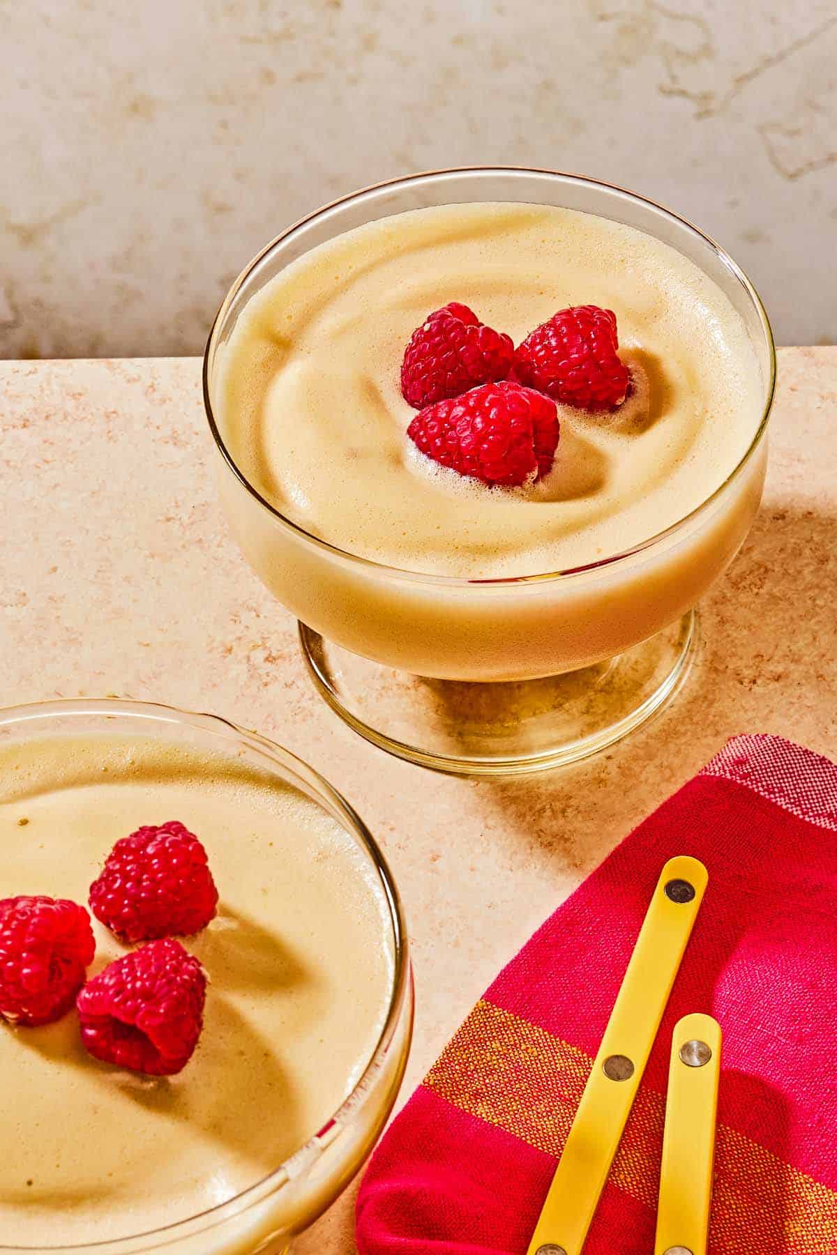 Two bowls of zabaglione topped with raspberries.