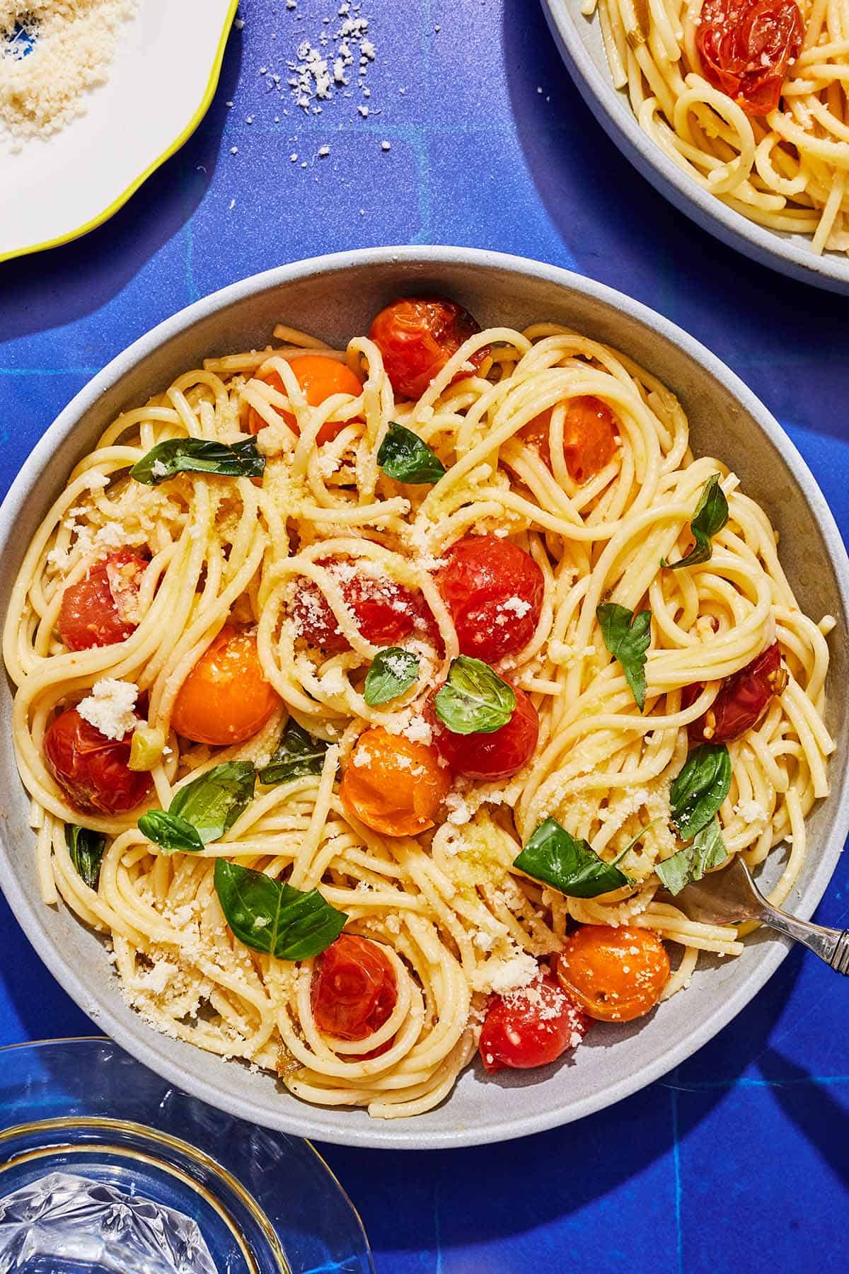 A serving of cherry tomato pasta in a bowl with a fork.