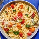 A serving of cherry tomato pasta in a bowl with a fork.
