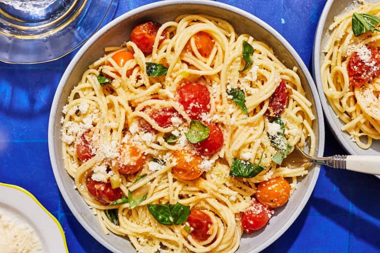 A serving of cherry tomato pasta in a bowl with a fork.