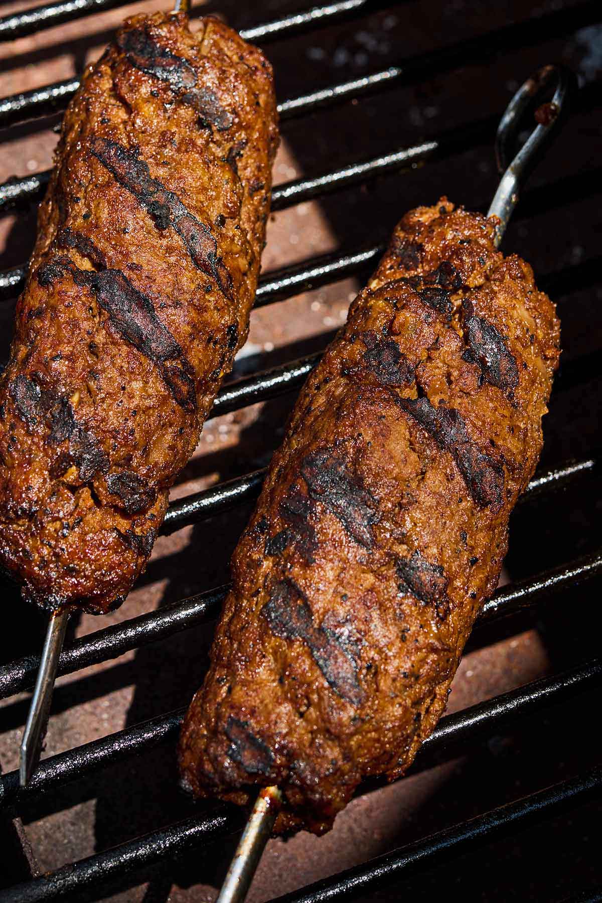 Two adana kebabs on a grill.