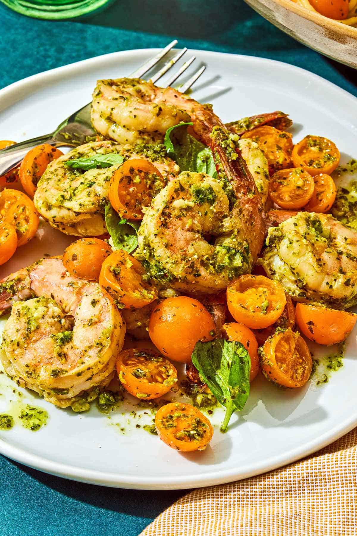A serving of pesto shrimp on a plate with a fork.