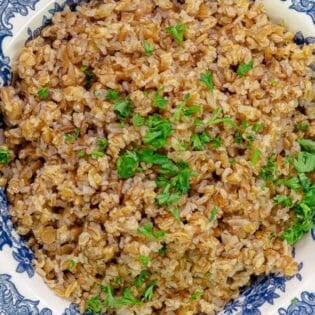Cooked bulgur in a bowl topped with chopped parsley.