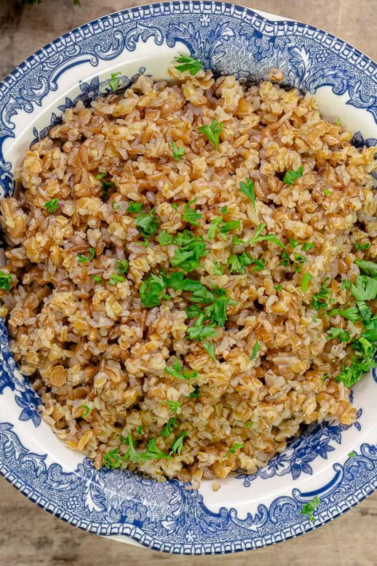 Cooked bulgur in a bowl topped with chopped parsley.