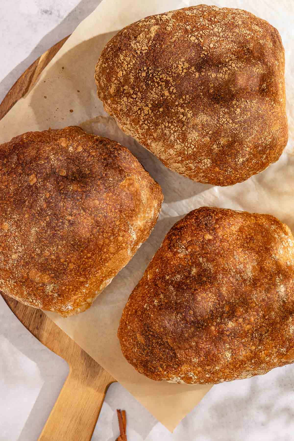 Three loaves of pan de cristal on a cutting board.