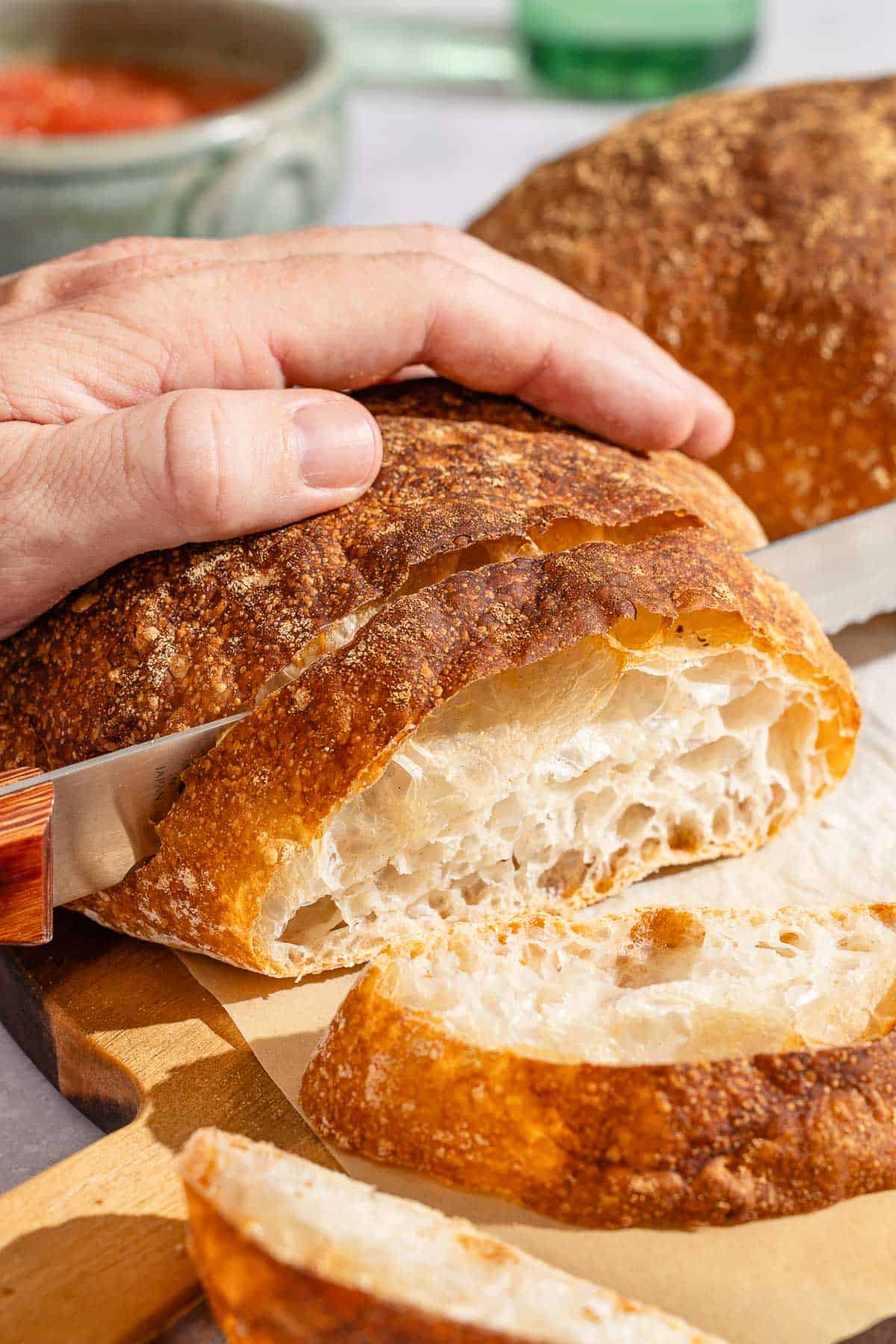 Pan de cristal being sliced on a cutting board.