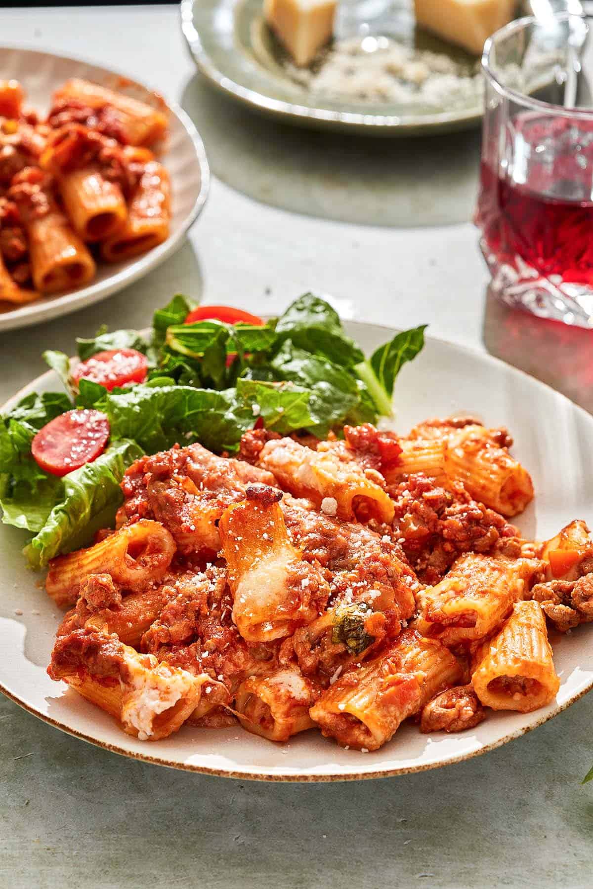 A serving of pasta al forno on a plate with a salad.