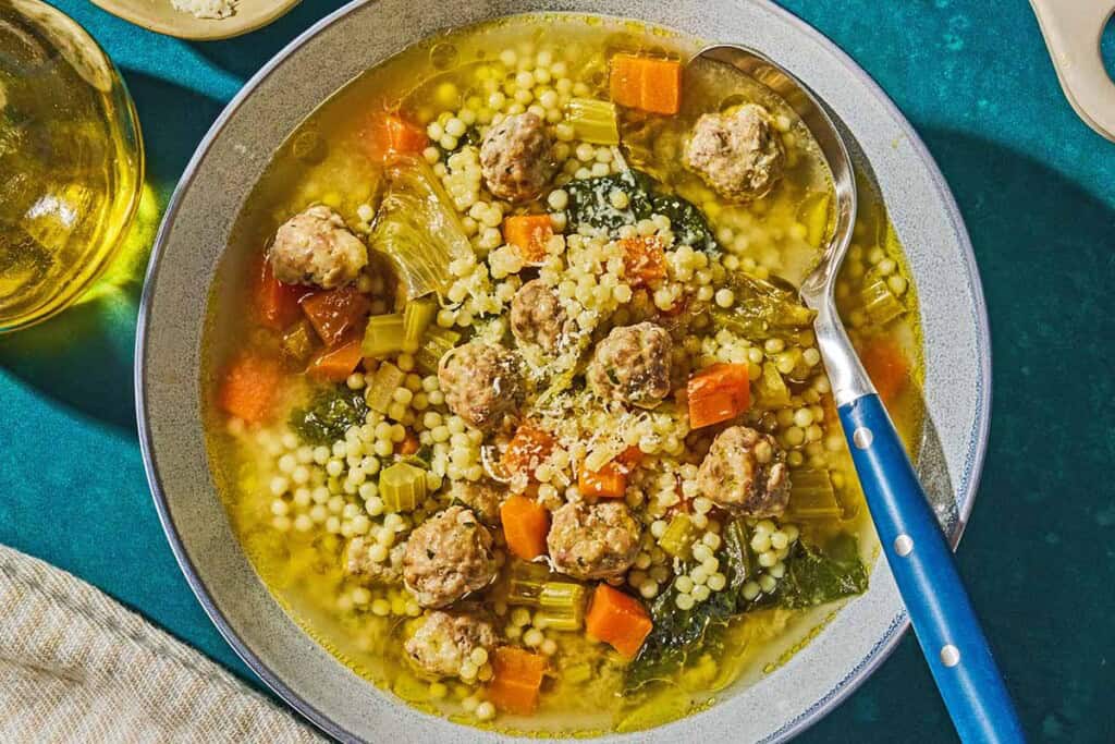Italian wedding soup in a bowl with a spoon.