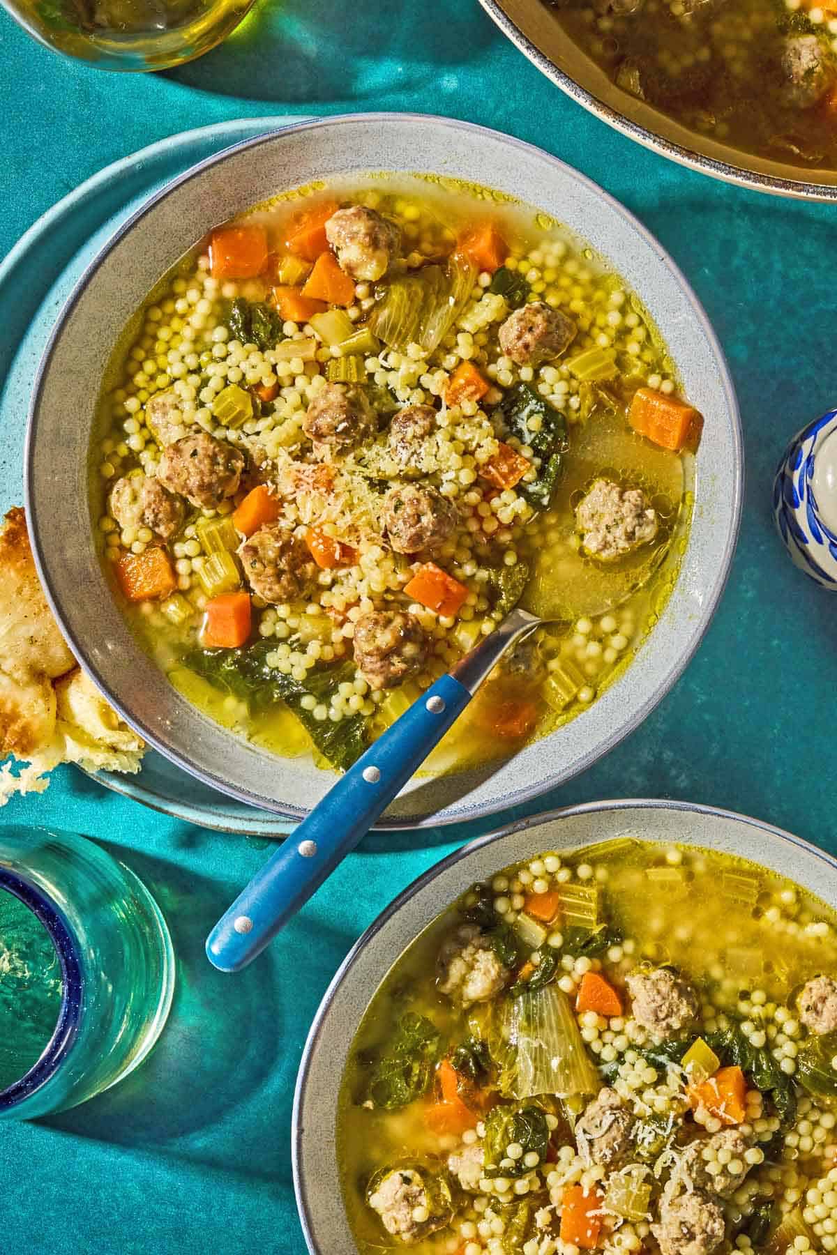 Two bowls of Italian wedding soup, one with a spoon.