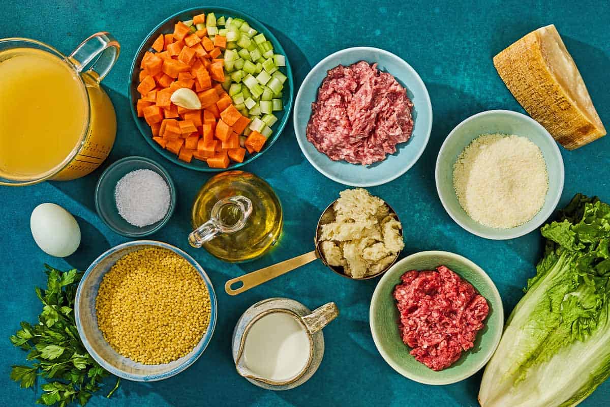 The ingredients for Italian wedding soup including ground meat, bread, milk, egg, parmesan, garlic, parsley, salt, olive oil, carrots, celery, chicken stock, escarole, and pasta.