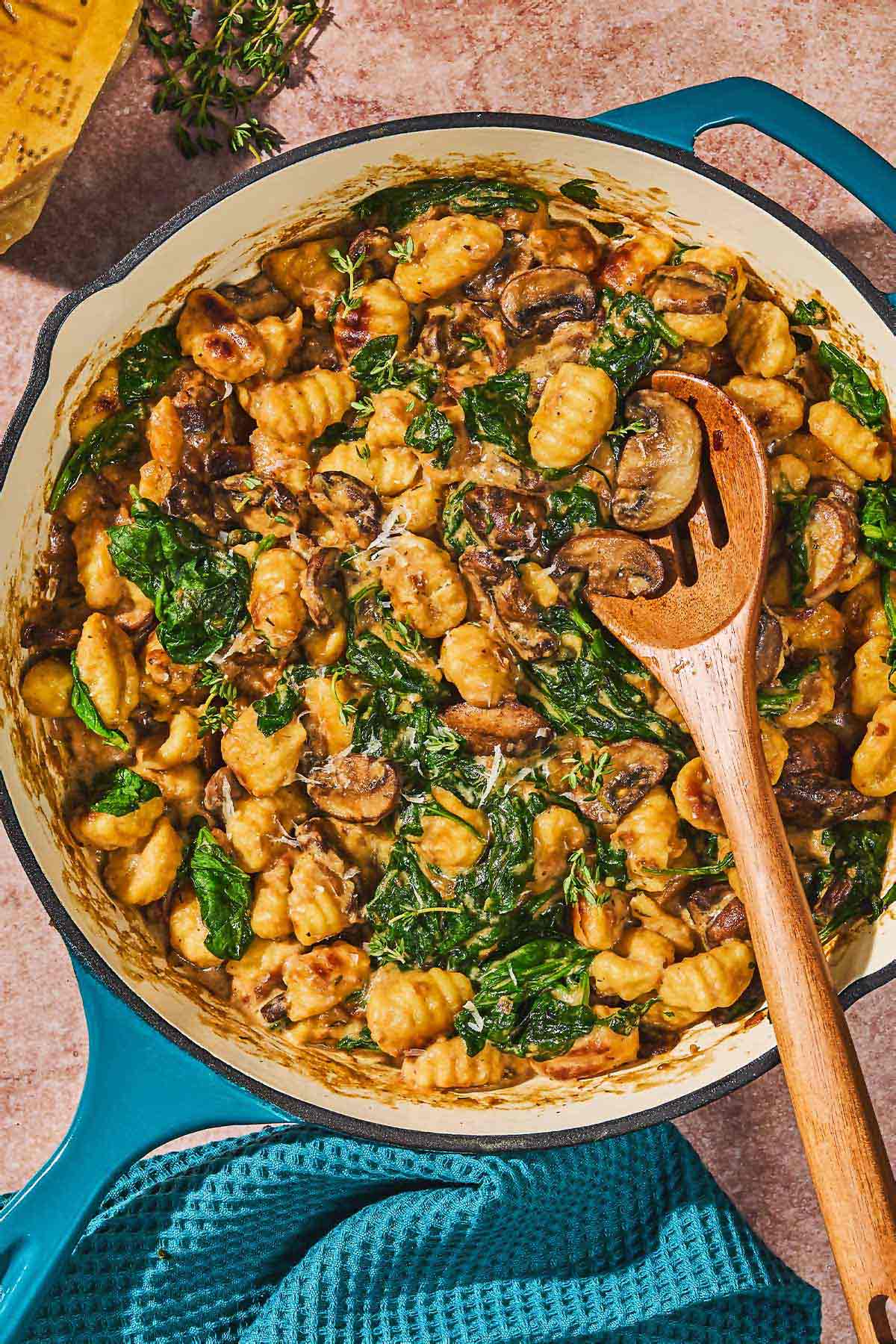 Mushroom gnocchi in a skillet with a wooden spoon.