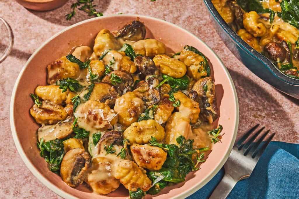 Mushroom gnocchi in a bowl next to a fork.