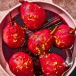 Poached pears in a bowl with a spoon.