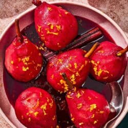 Poached pears in a bowl with a spoon.