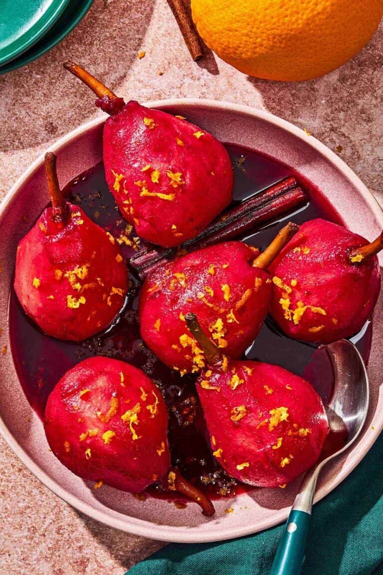 Poached pears in a bowl with a spoon.