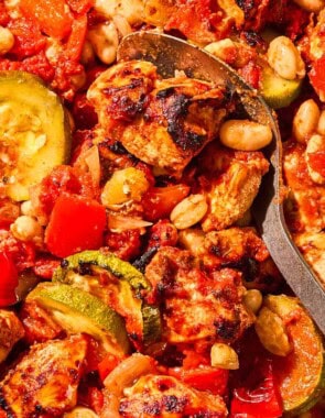 Sheet pan chicken and vegetables in a bowl with a spoon.