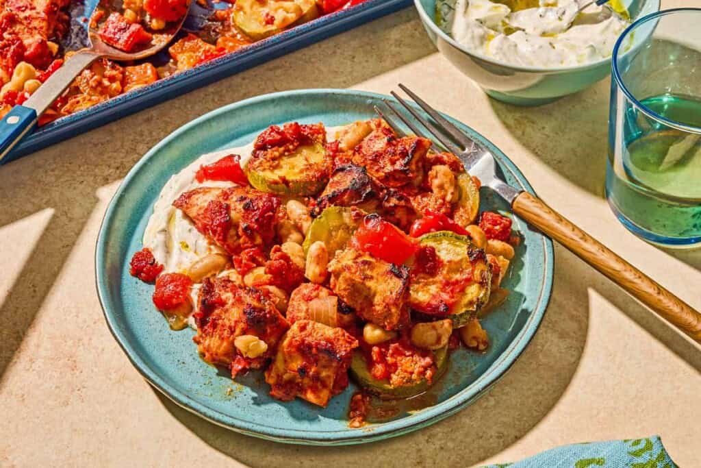 Sheet pan chicken and vegetables on a plate with a fork.