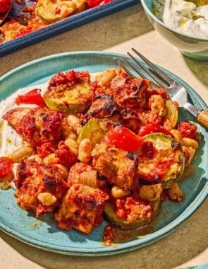Sheet pan chicken and vegetables on a plate with a fork.