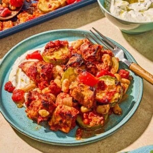 Sheet pan chicken and vegetables on a plate with a fork.