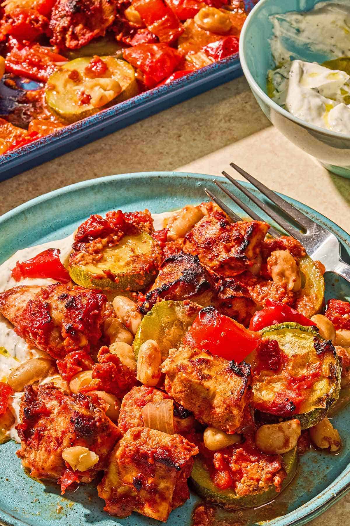 Sheet pan chicken and vegetables on a plate with a fork.