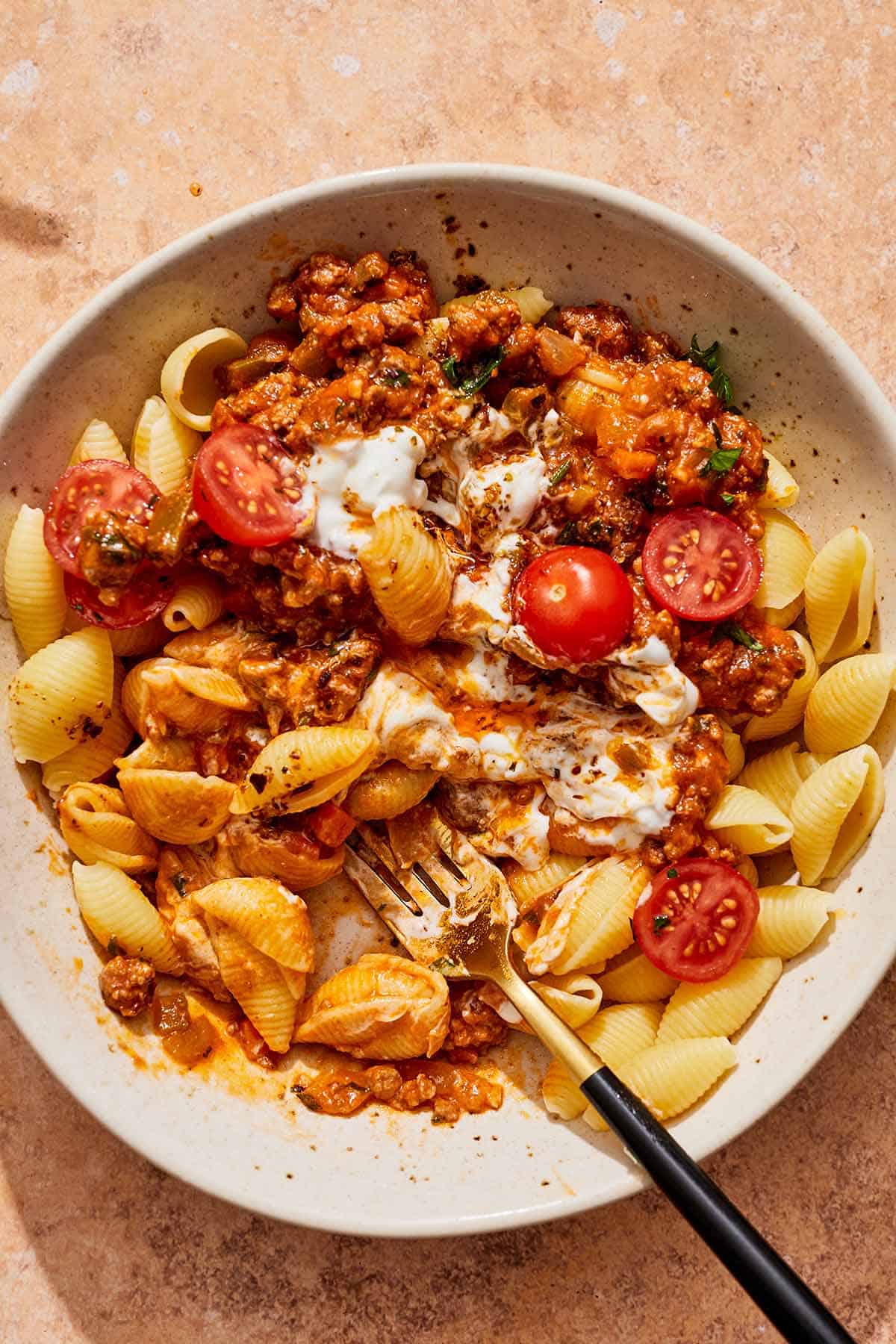 A partially eaten bowl of the Turkish pasta with a fork.
