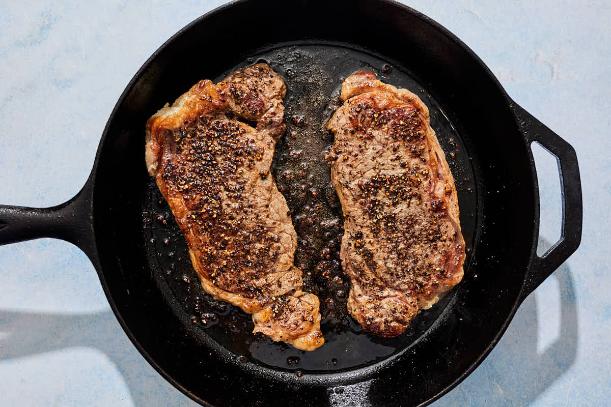 The steak for the steak au poivre being seared in a cast iron skillet.