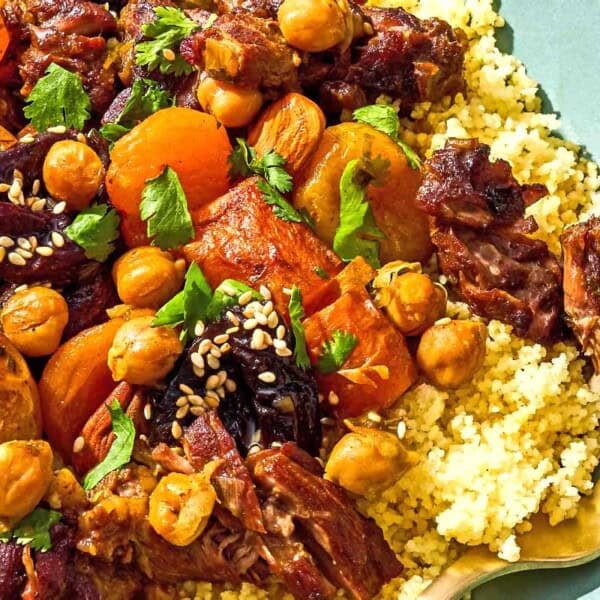 A serving of beef tagine over couscous in a bowl with a fork.