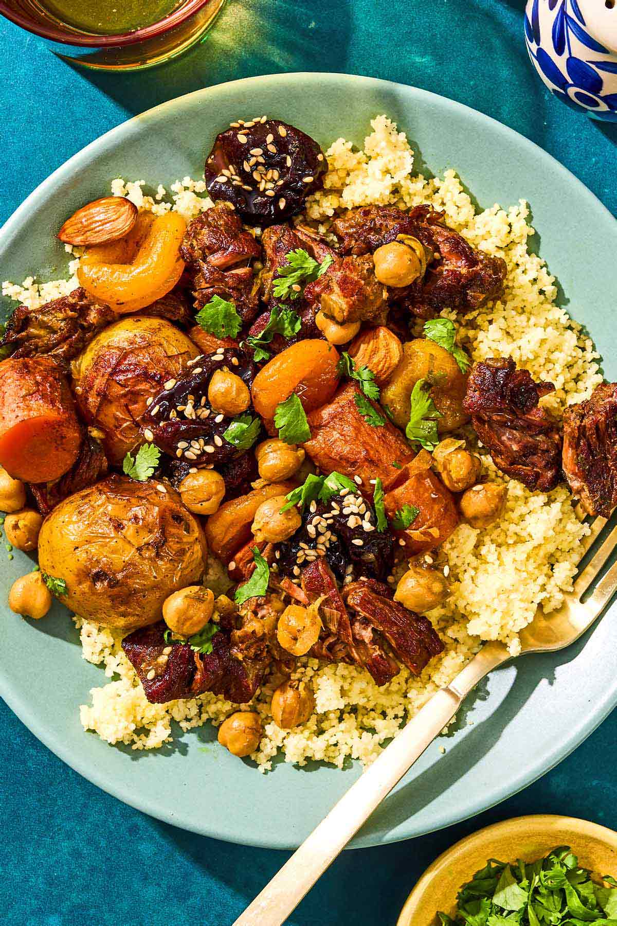 A serving of beef tagine over couscous in a bowl with a fork.