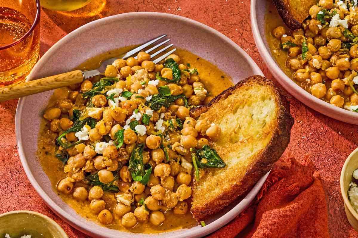 A serving of the chickpea skillet in a bowl with a slice of toast and a fork.