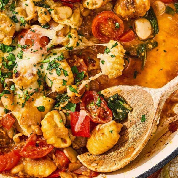 Skillet gnocchi in a skillet with a wooden spoon.