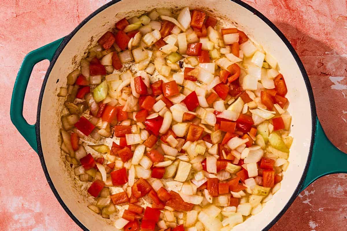 The chopped red bell pepper and onion being sautéed in the skillet.