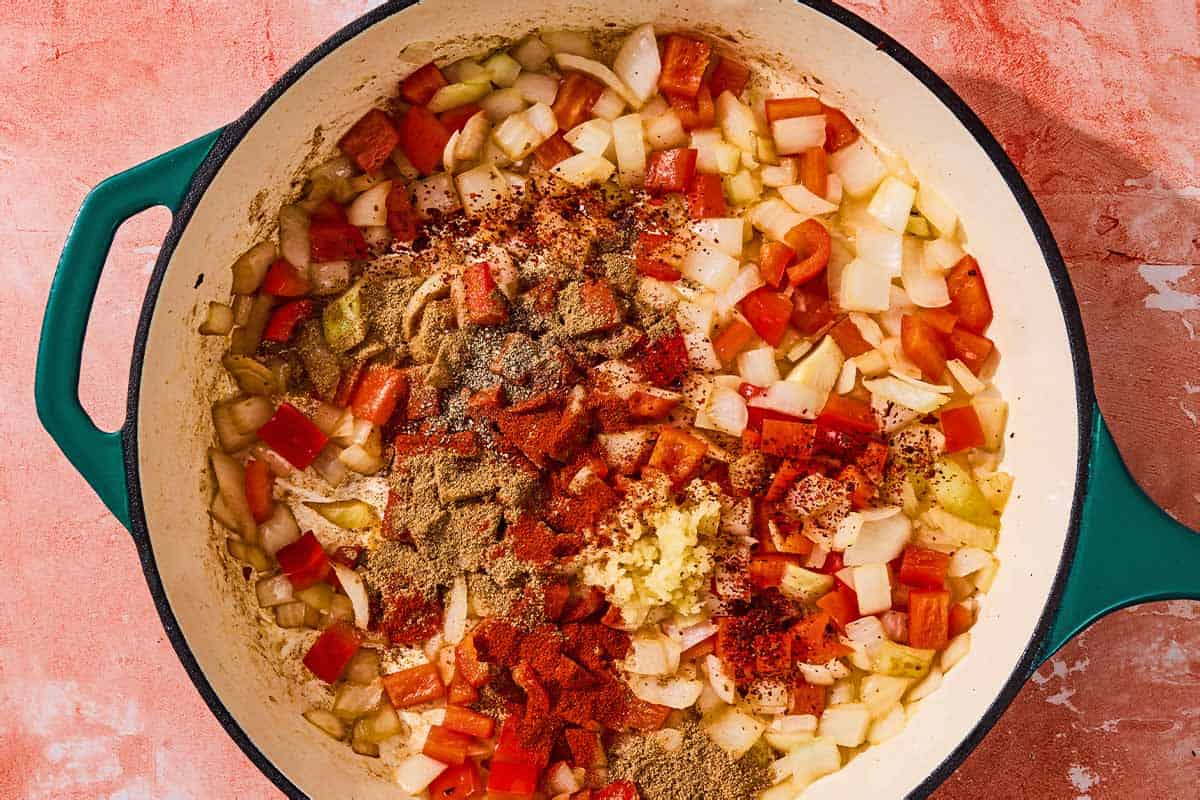 The seasonings added to the sautéed onion and red bell pepper in the skillet.