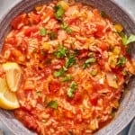 Tomato rice soup in a bowl with lemon wedges.