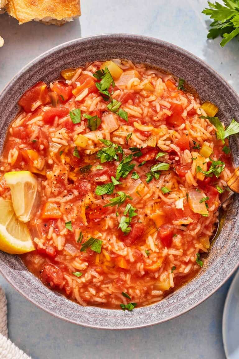 Tomato rice soup in a bowl with lemon wedges.