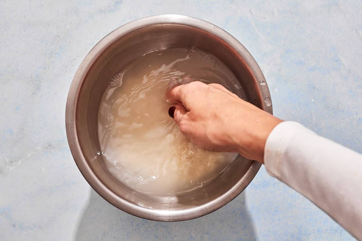 The rice for the tomato rice soup being rinsed in a bowl.
